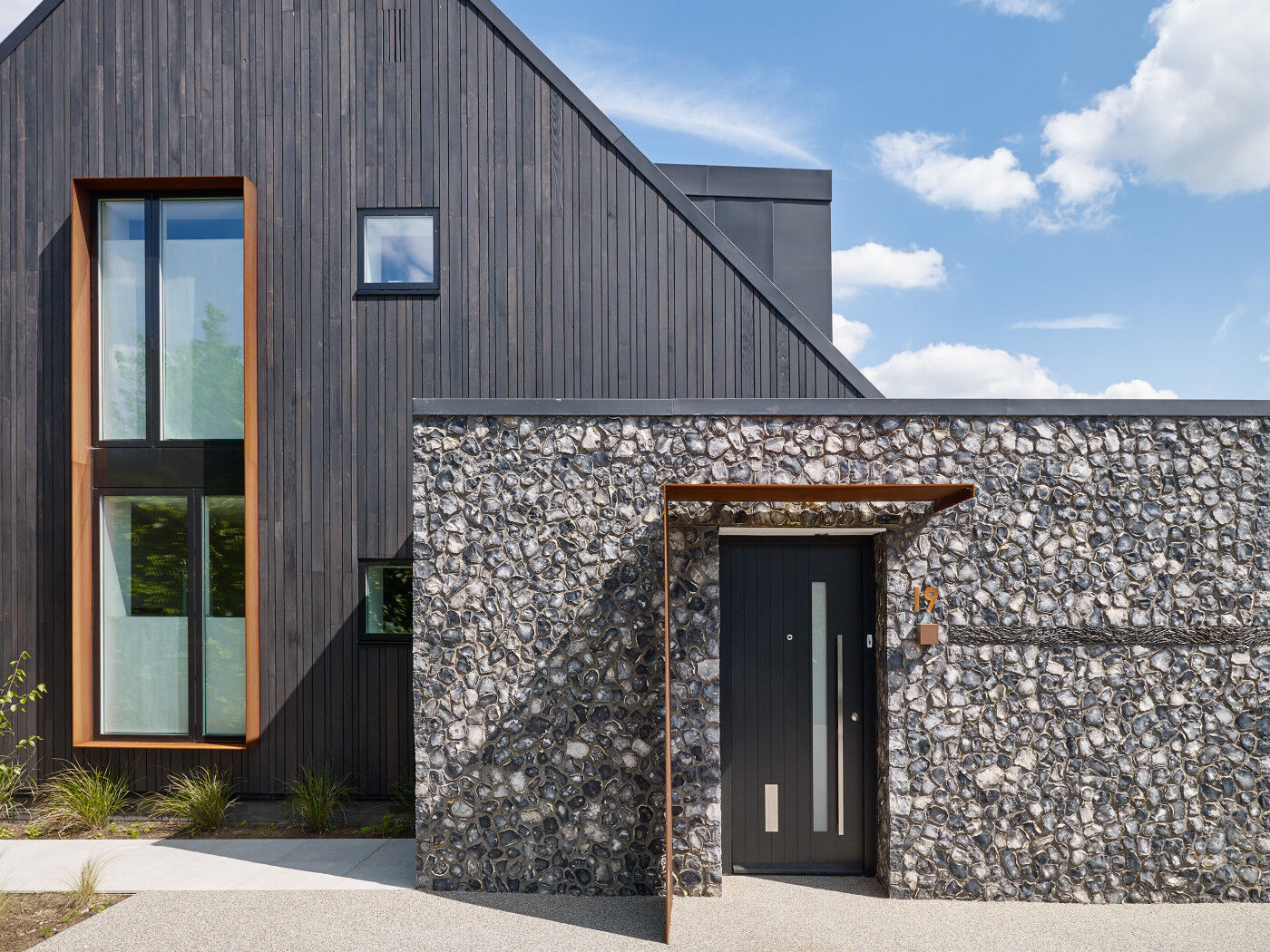 Rust detailing in the house number and partial canopy brings everything together in this mixed material build