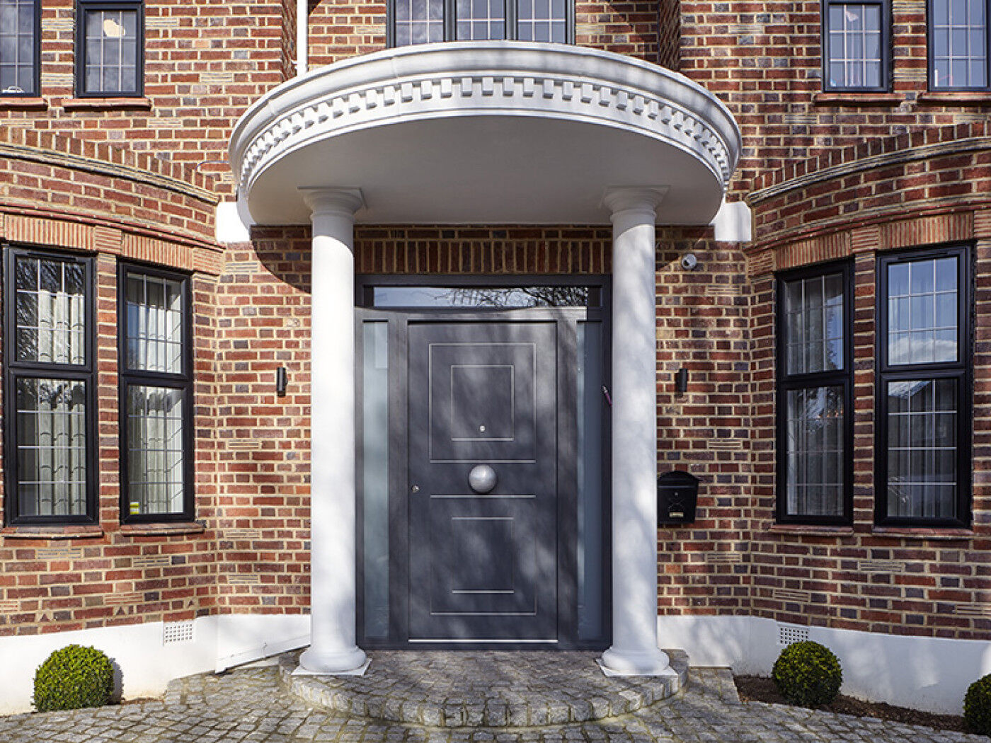 Black windows and a white portico porch make this dark grey door stand out