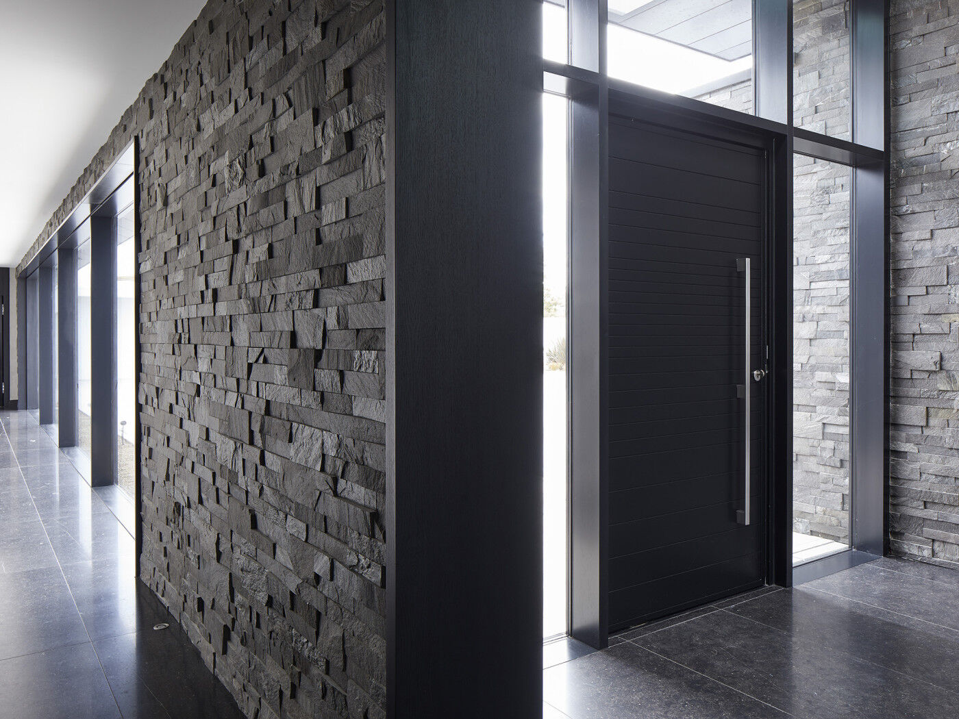 A modern classic, flanked by plenty of glass, this black door adds timeless elegance to the overall aesthetic of the house