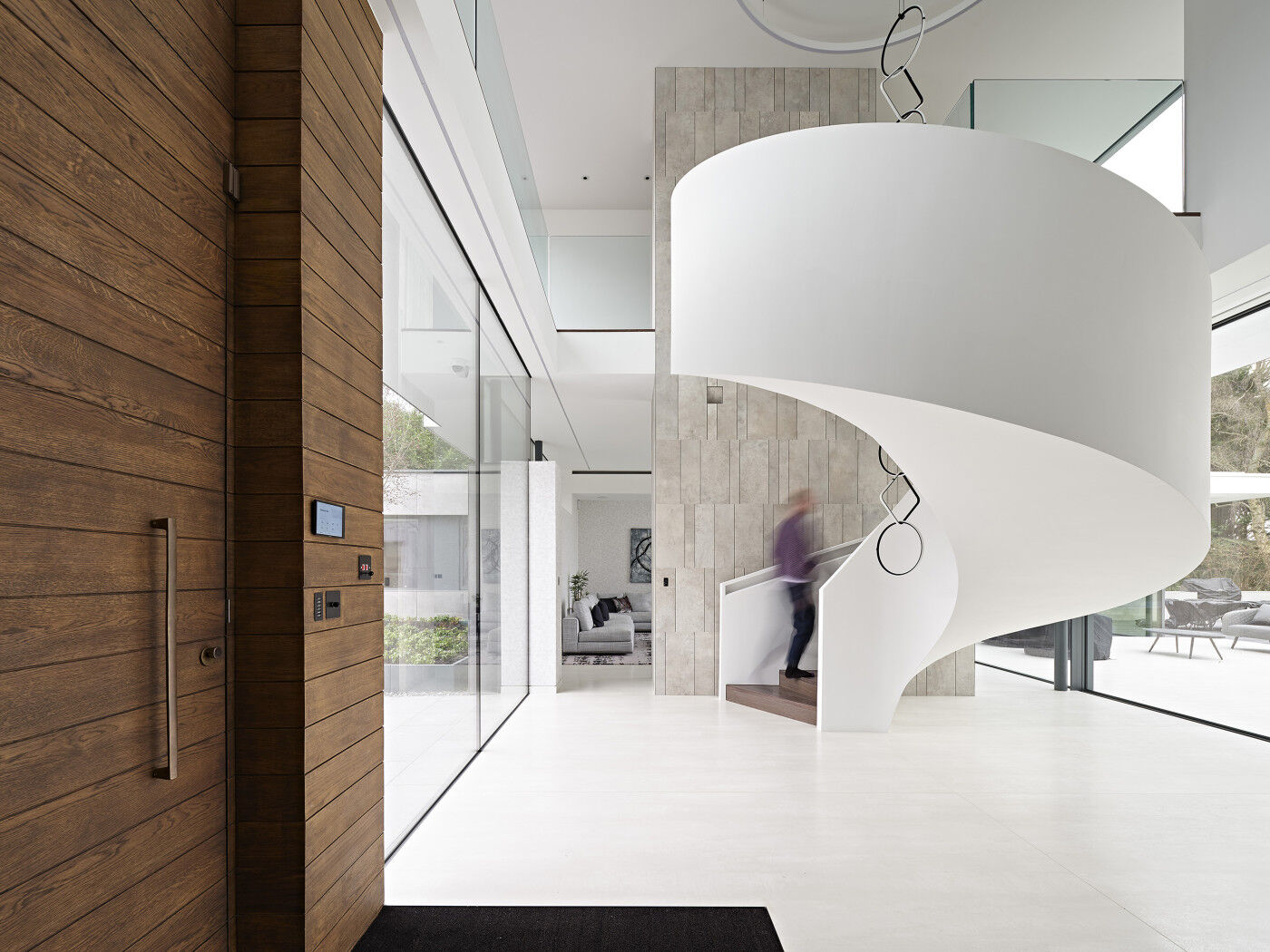 The walnut-stained door adds warmth to the light interior as you step into the hallway, where the spiral staircase takes pride of place