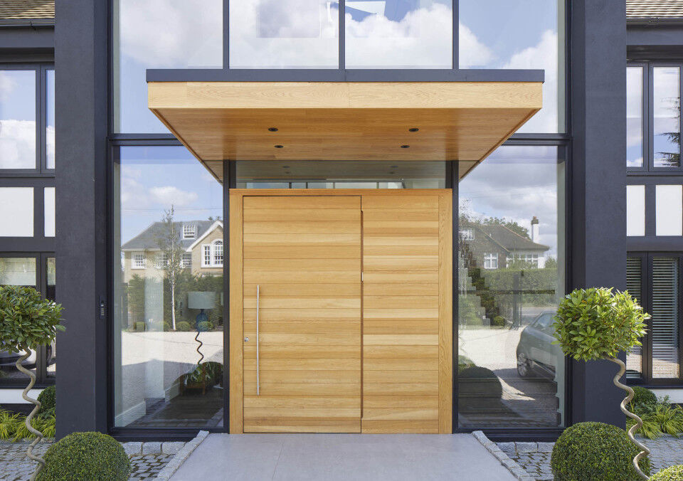 This metal & wooden front door canopy extends a long way in front of this pivot door to give shelter from sun & rain
