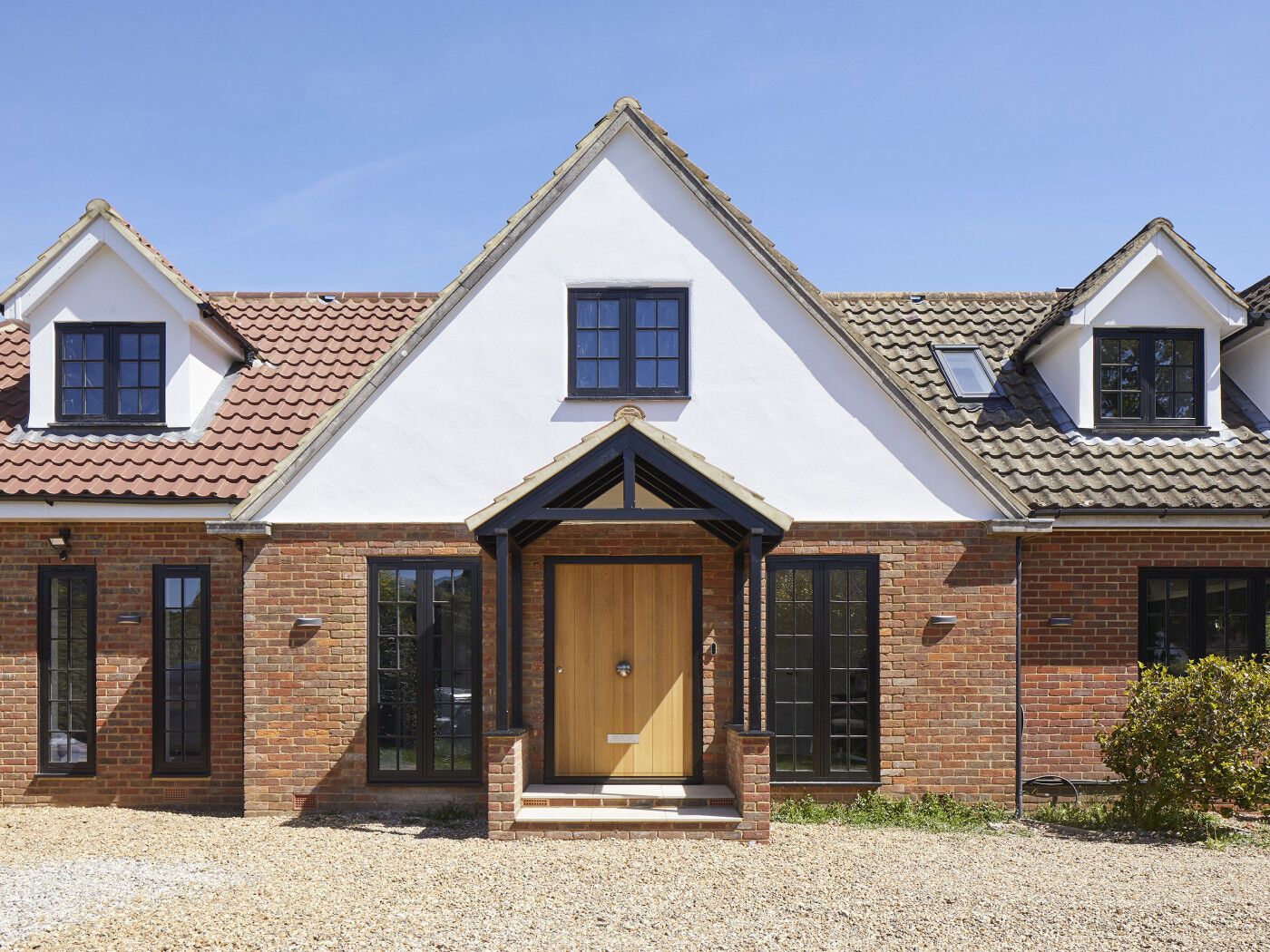 The black windows on this traditional house work perfectly with the lighter European oak front door and red brick of the facade 