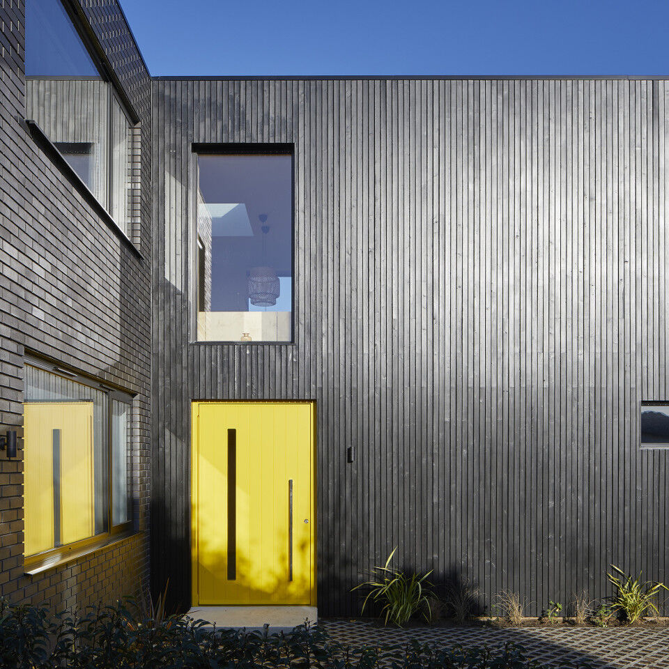 here a striking yellow door really makes a statement against the black cladding