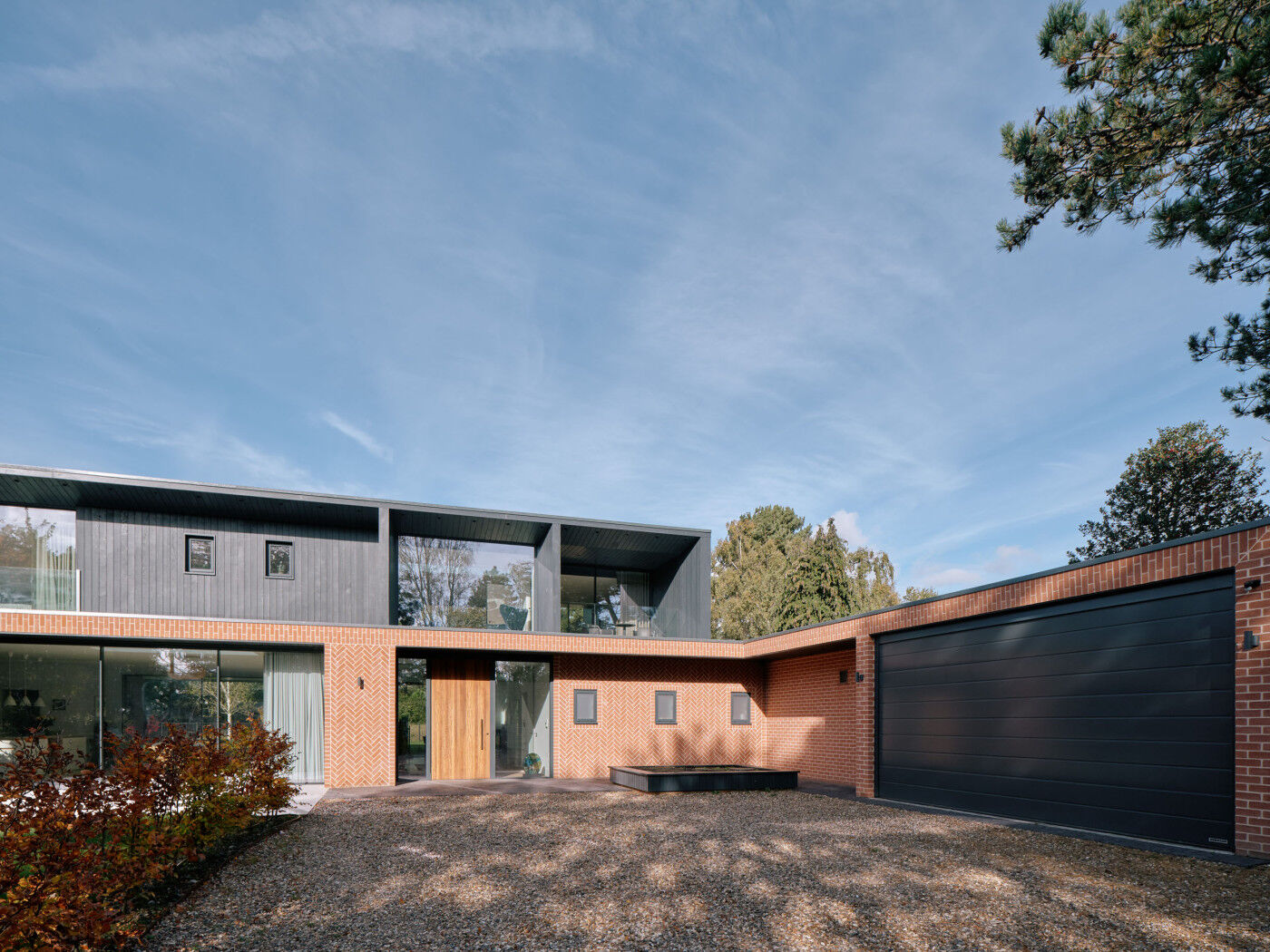 Black cladding and black garage doors create unity and draw attention to the front door.