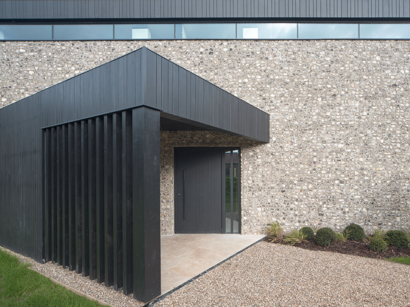 Black timber cladding, Flemish Bond brickwork and flint create a contemporary twist.