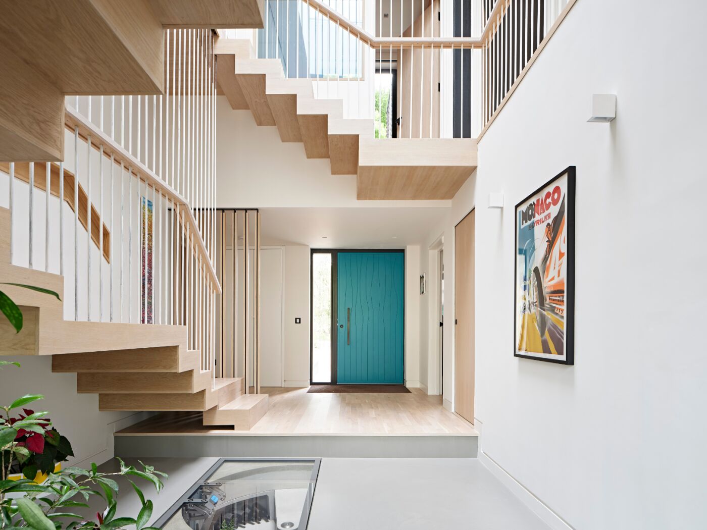 Sculptural and perfectly balanced, the bright door shines against the pale wood and white walls