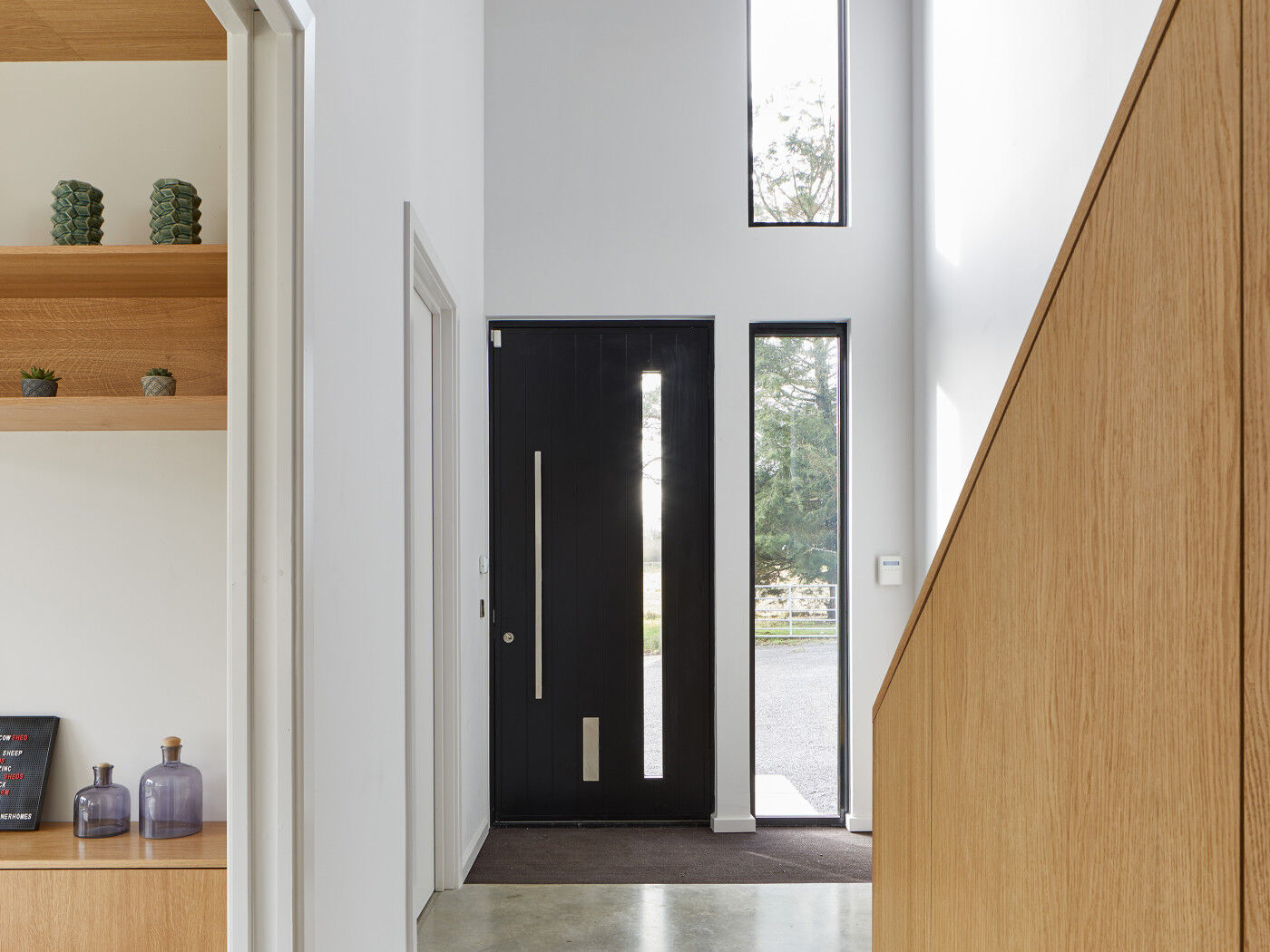 And inside the modern black door sits in a fresh hallway with ample light provided by the door's glass panel & additional windows