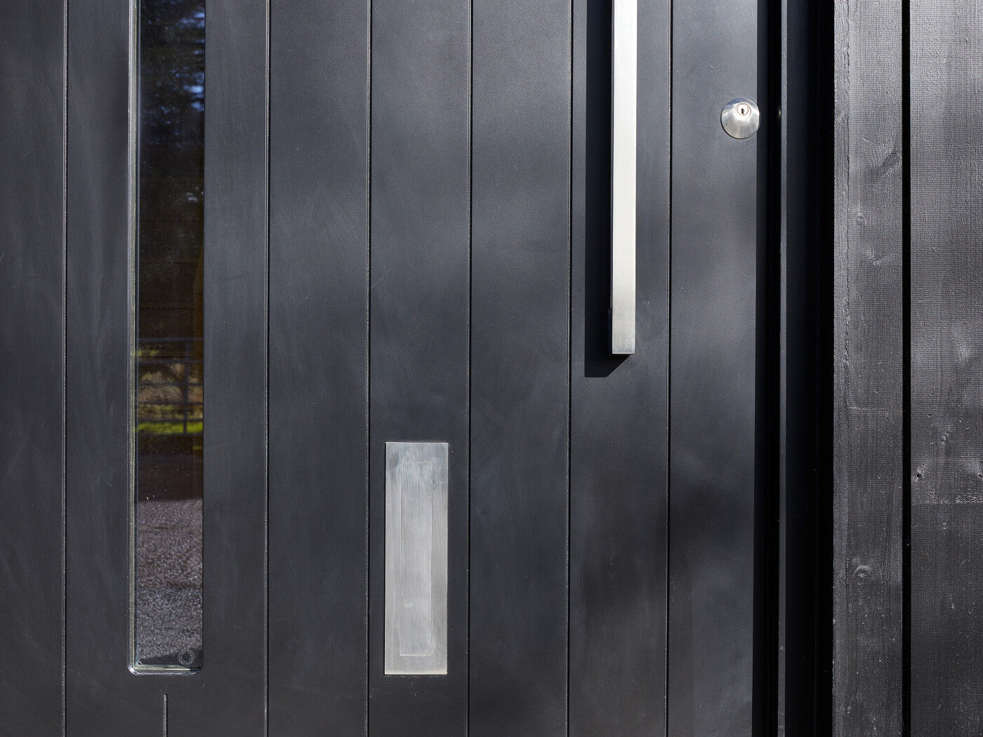 This black door design blends seamlessly into the vertical black cladding 