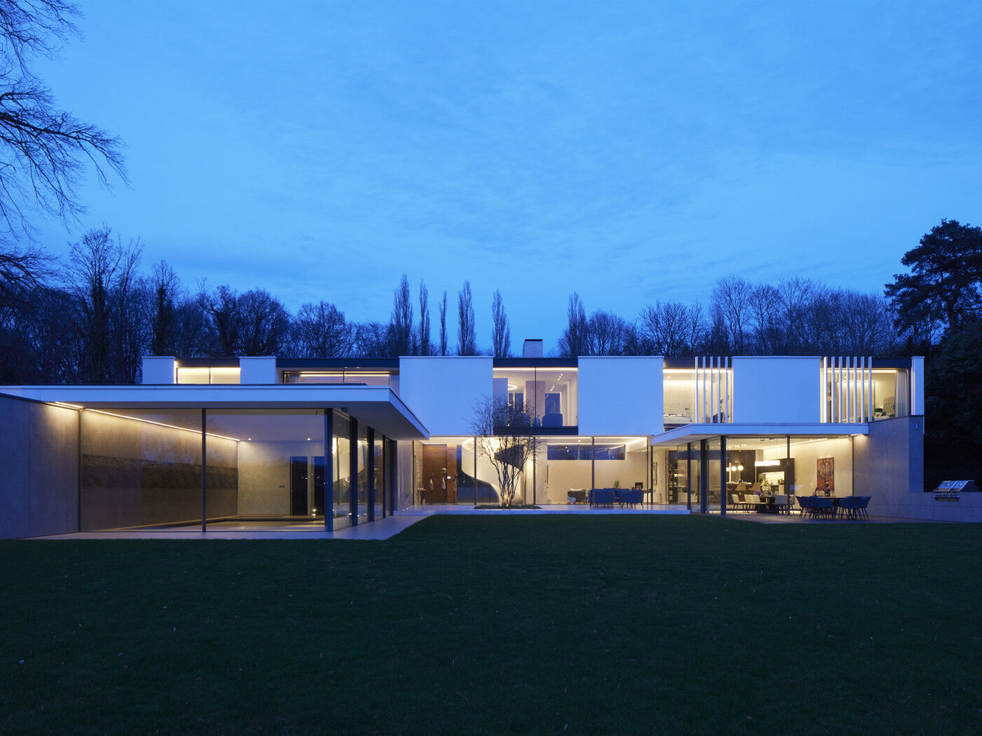 As night falls, the house is lit up and the expansive back garden creates the same impressive views as the front entrance