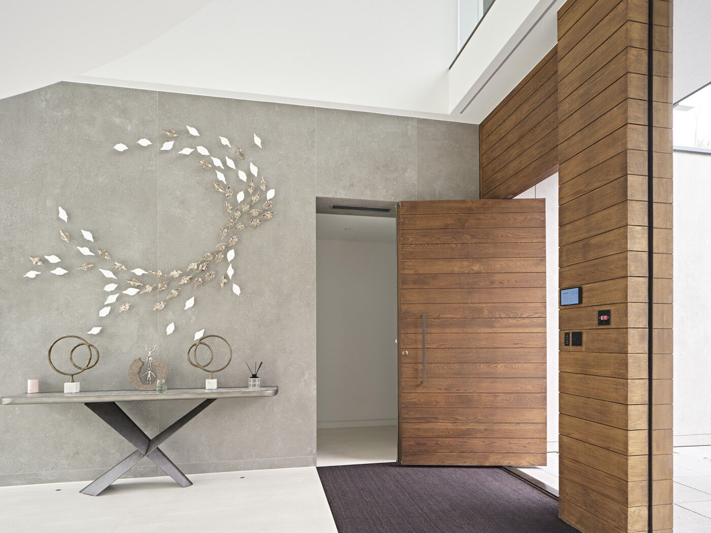The wooden front door works beautifully with the light concrete walls & white floor of the interior