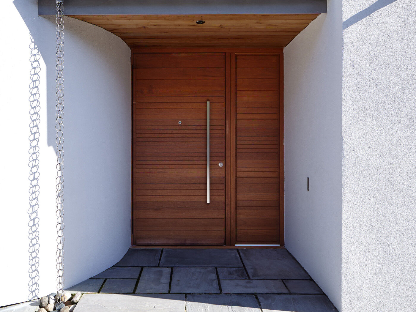 This iroko front door features a matching wood side panel to aid the perception of a wider opening