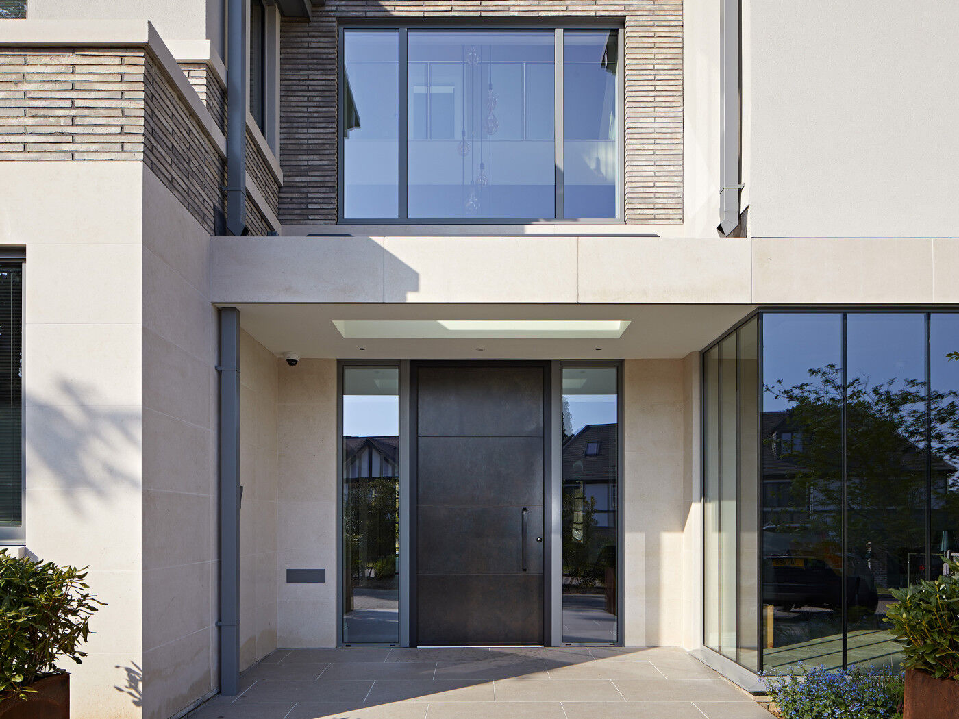 This beautiful oversized copper door sits between two glass sidelights & stands out against the neutral front facade