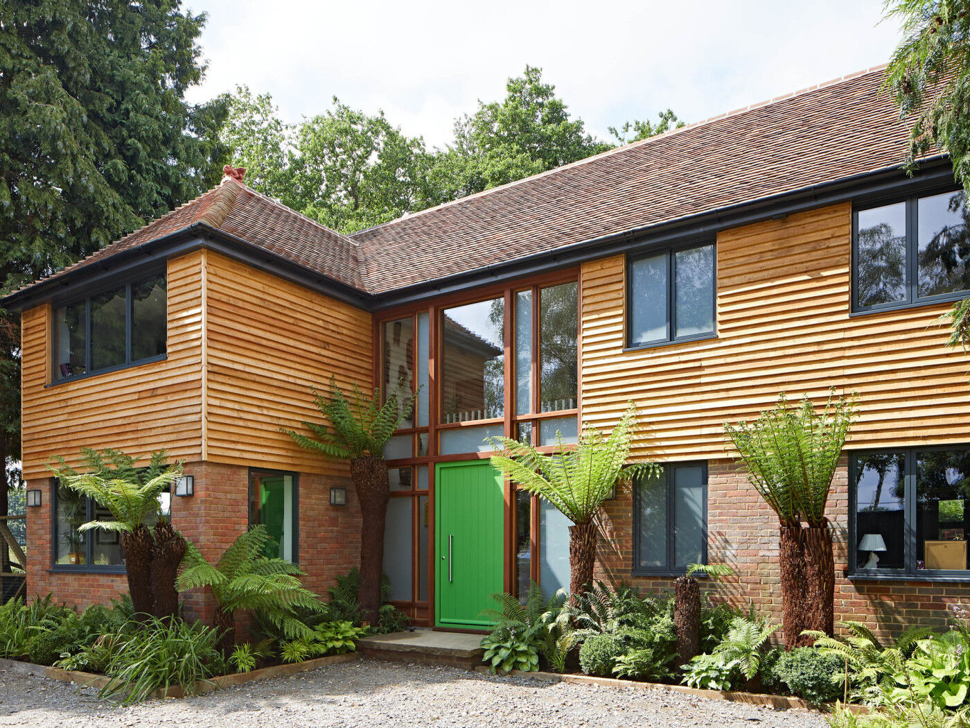 With more neutral cladding and brick tones, this bold green door adds a touch of the tropical to this beautiful property