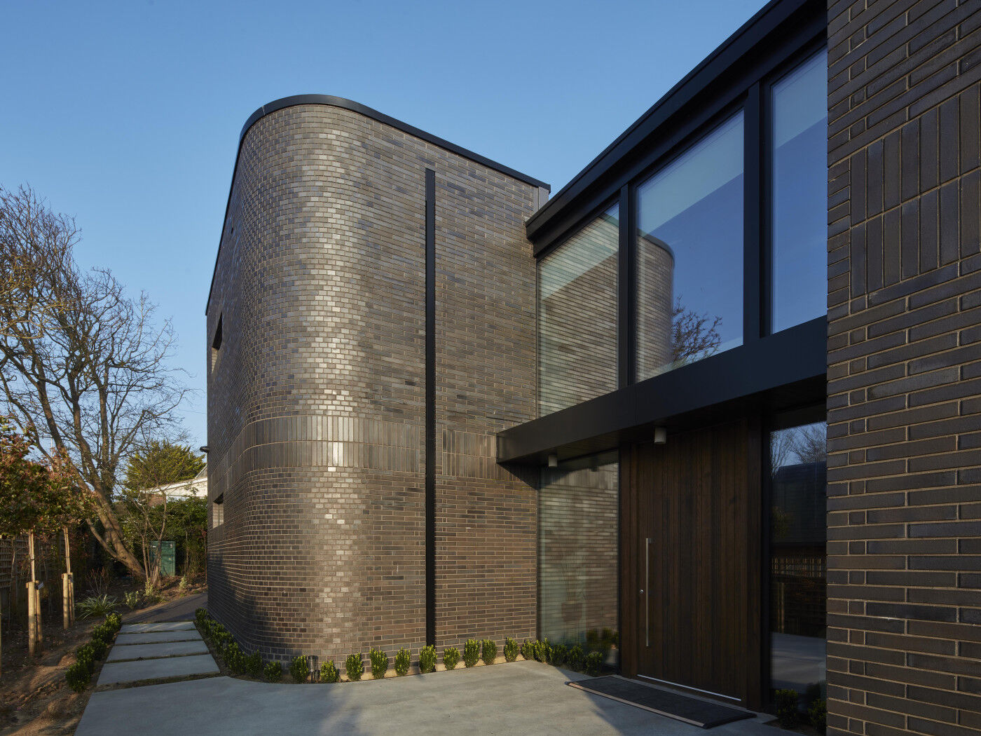 A fumed oak door works perfectly with the dark bricks of this modern home.