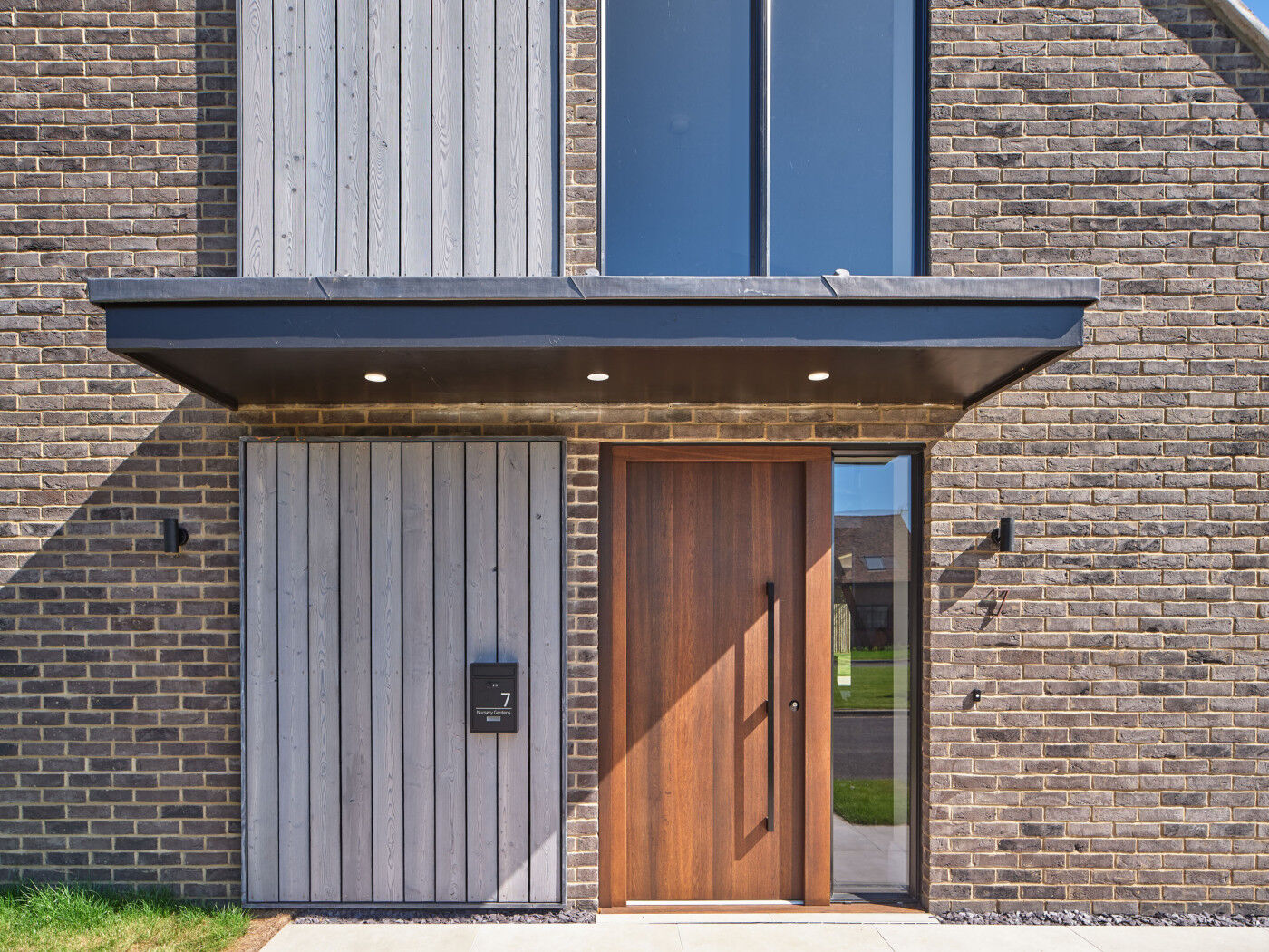 The fumed oak door brings warmth to property standing out from the brown bricks and grey cladding.