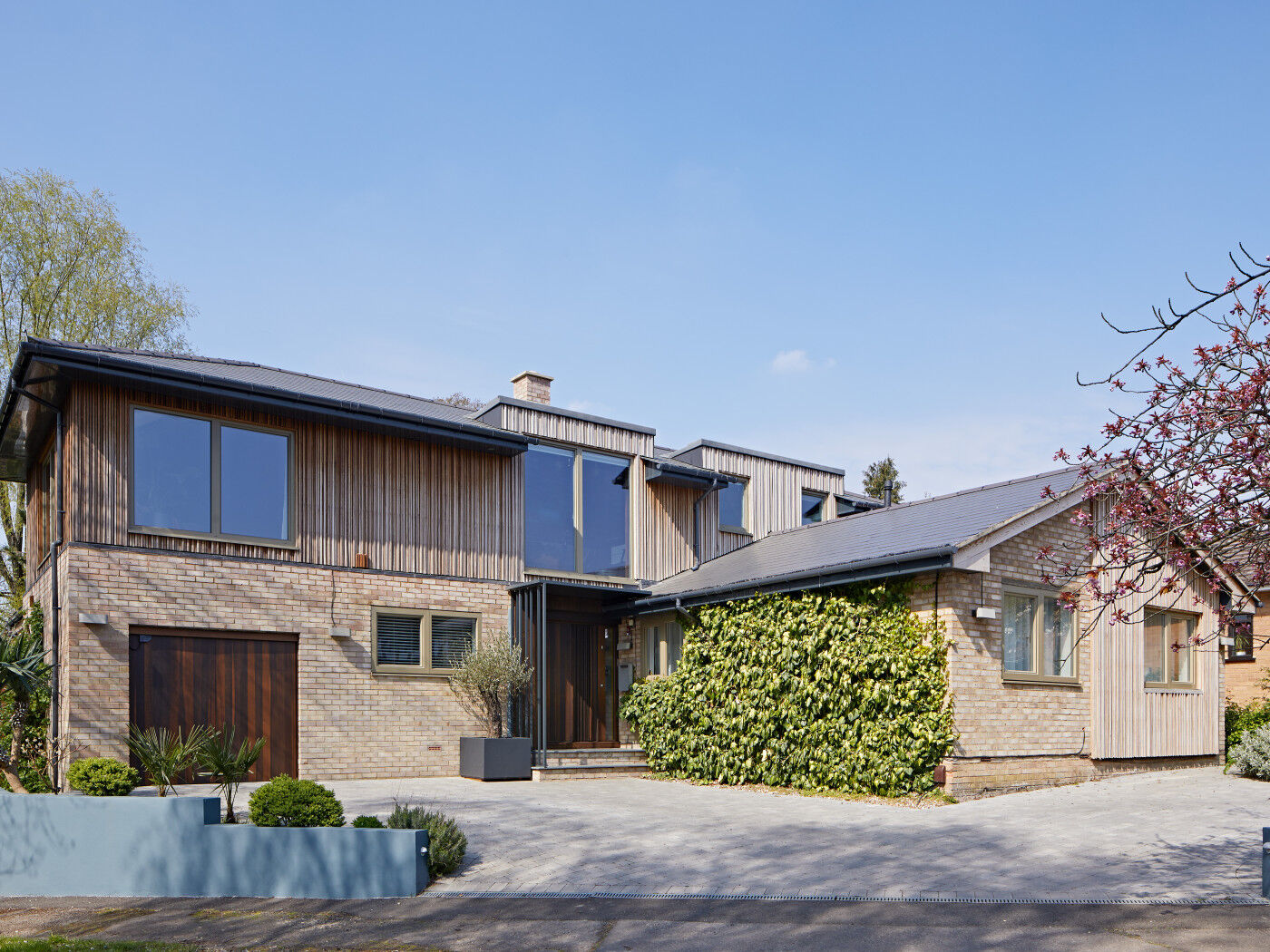 Pale bricks and olive window frames create the perfect backdrop for fumed oak front and garage doors.