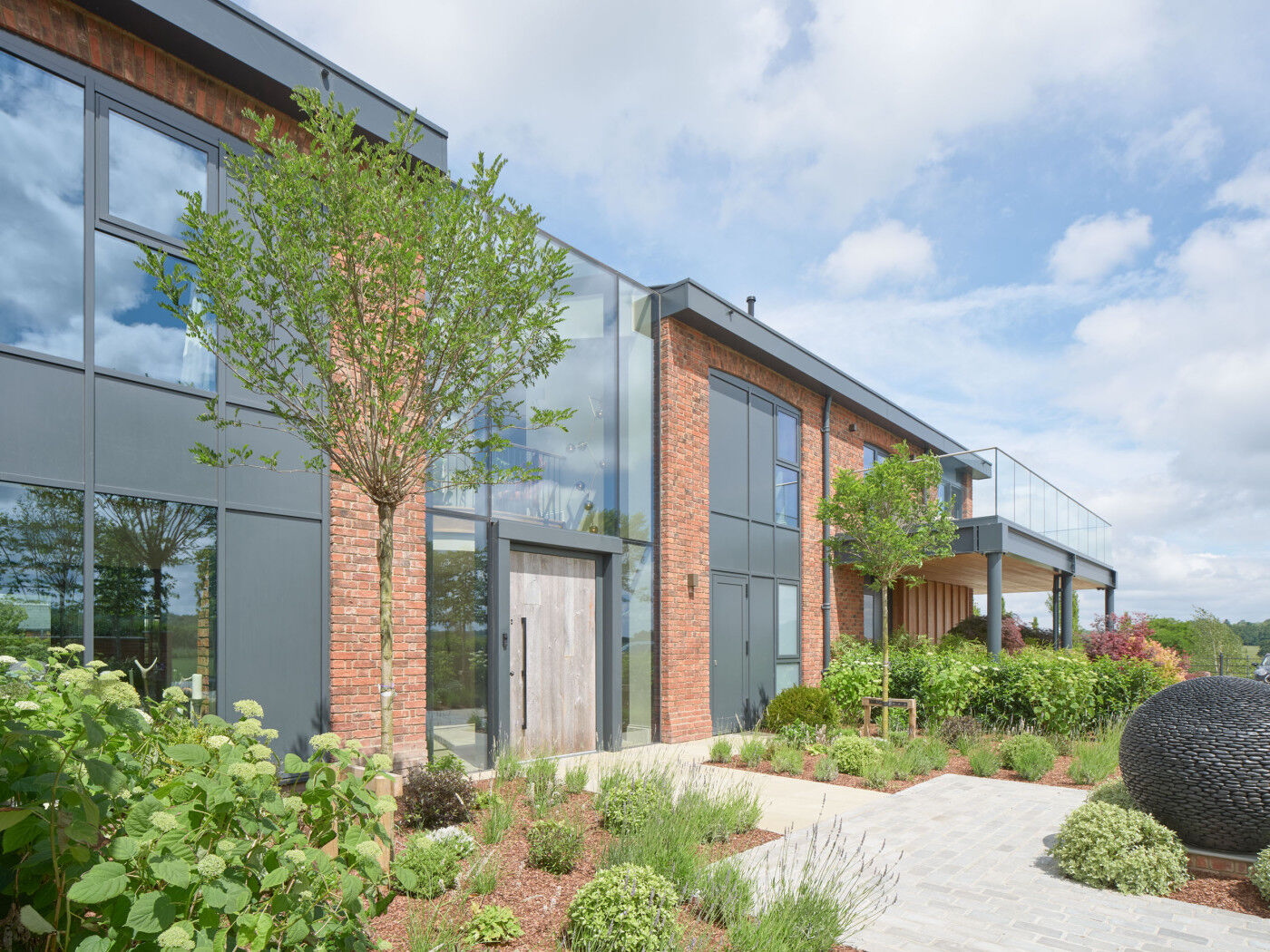 This barn conversion features red brick, grey frames and a reclaimed Barn door
