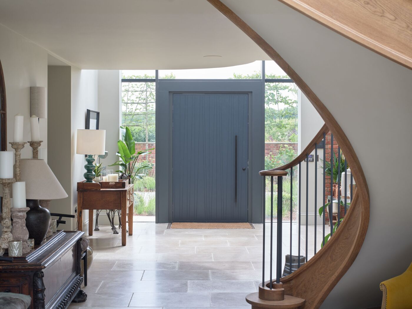 A large door finished in grey blue set against architectural glazing and feature staircase.