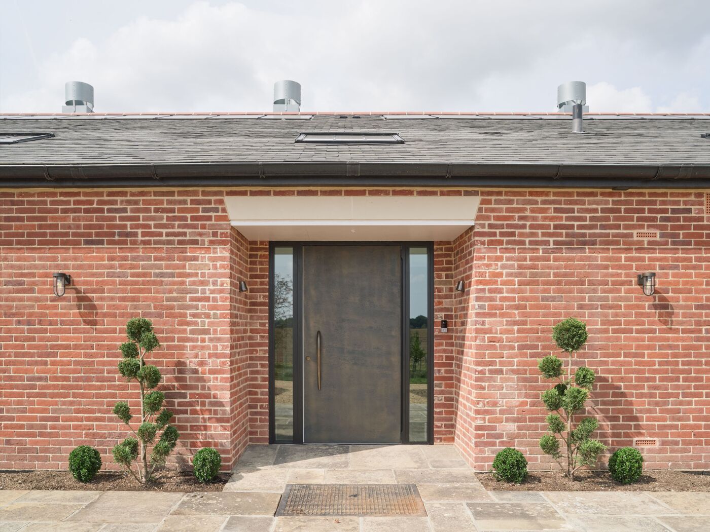 This imposing bronze door stands out from the red brick and grey roof.