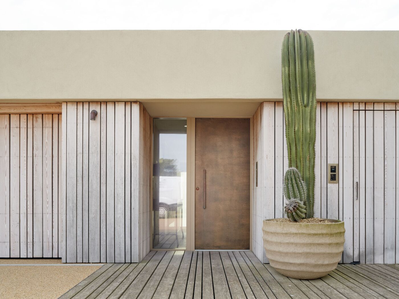 The bronze front door with BZ5 handle contrasts with the silver tones of the wood cladding.