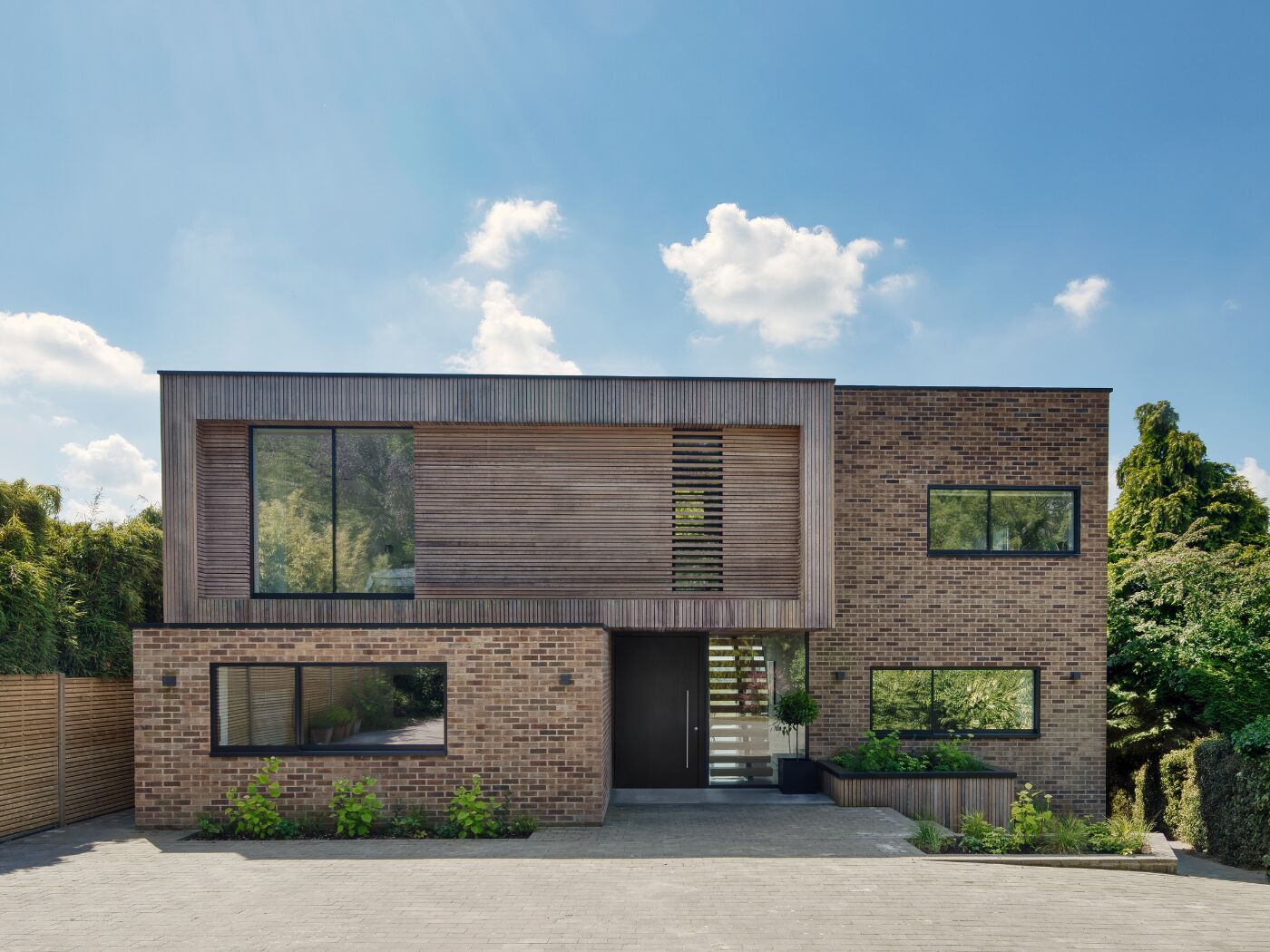 The oak door with ebony oil contrasts beautifully with the brick and cladding finishes.