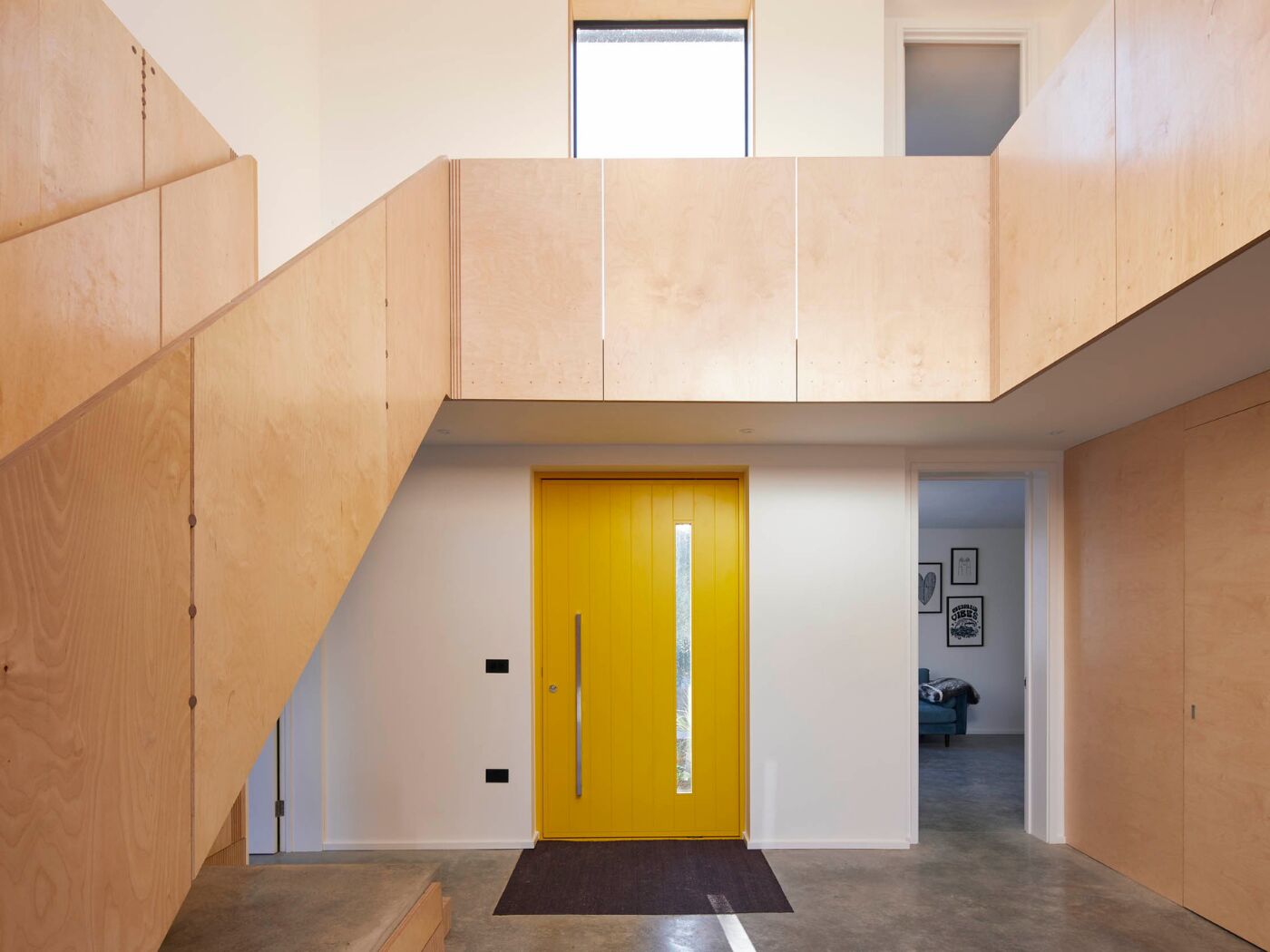 Concrete floors, plywood stairs, white walls and a Terano door in yellow make a contemporary statement.