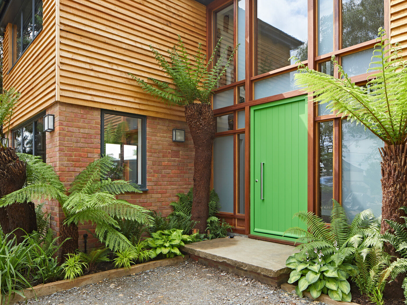 This vibrant green Porto door (painted RAL 6018) strikes a glorious note of the tropical against timber cladding and red brick 